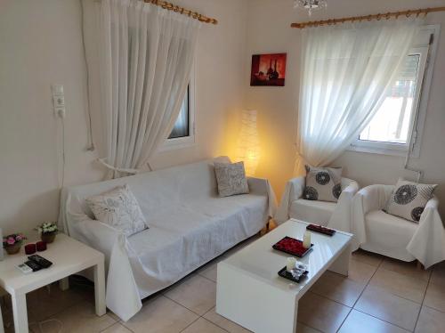 een woonkamer met een witte bank en 2 tafels bij Yiannis Appartments 