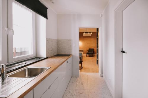 uma cozinha com armários brancos, um lavatório e uma janela em Między Murami em Toruń
