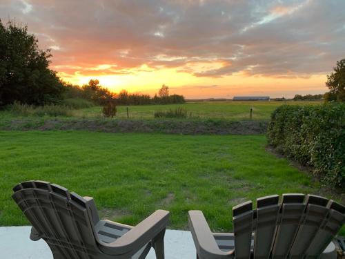 two chairs sitting on a patio with a view of a field at Silo 161 in Ruinerwold