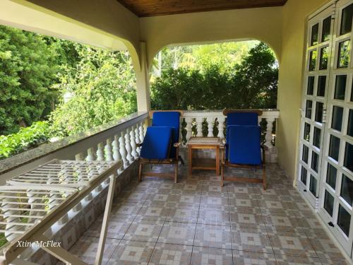 a porch with two blue chairs and a table at Captain's Villa in Takamaka