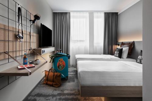 um quarto de hotel com duas camas e uma televisão em Moxy Duesseldorf City em Düsseldorf