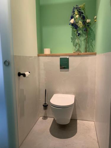 a bathroom with a toilet and a vase of flowers at Silo 161 in Ruinerwold