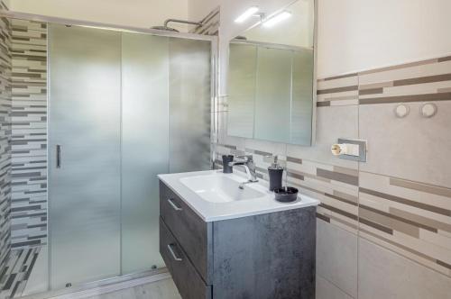 La salle de bains est pourvue d'un lavabo et d'une douche en verre. dans l'établissement Domus Lucis Apartment Terrace & Private Parking, à Marinella di Sarzana