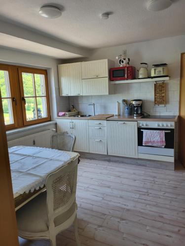 eine Küche mit weißen Schränken und einem Tisch mit Stühlen in der Unterkunft Wohnung Elbblick in Königstein an der Elbe