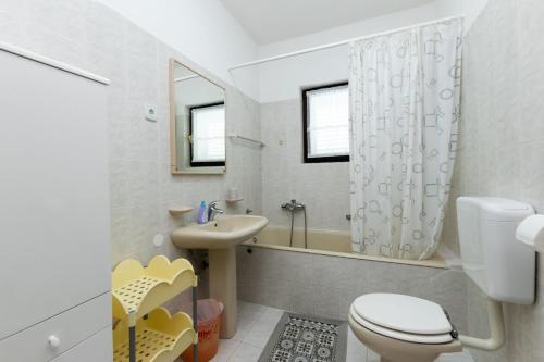 La salle de bains est pourvue de toilettes, d'un lavabo et d'une douche. dans l'établissement Apartments Anka, à Rab