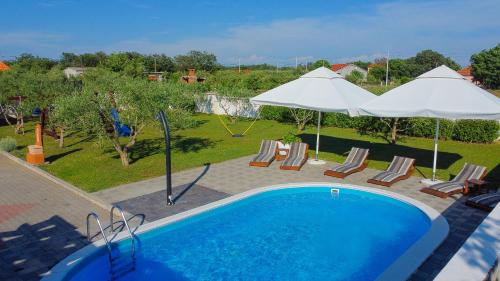 a swimming pool with chairs and umbrellas next to at House Leonardo in Galovac