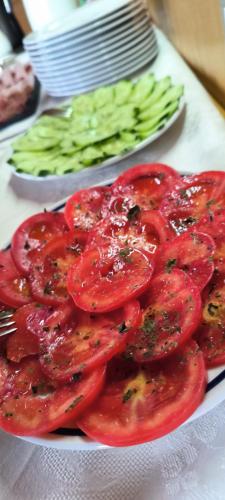 a plate of tomatoes and green vegetables on a table at Zimmervermietung Gröberhof in Schenna