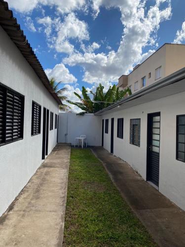 een steegje tussen twee witte gebouwen met een blauwe lucht bij Suítes Algth in Uberlândia