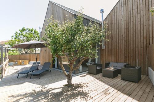 a patio with a tree and chairs and an umbrella at Villa Arneiro II in Vimeiro