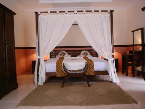 a bedroom with a canopy bed with two chairs at Swaloh Resort & Spa in Kalangbret