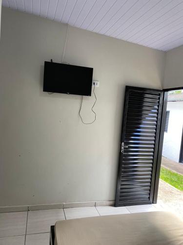 een slaapkamer met een flatscreen-tv aan de muur bij Suítes Algth in Uberlândia