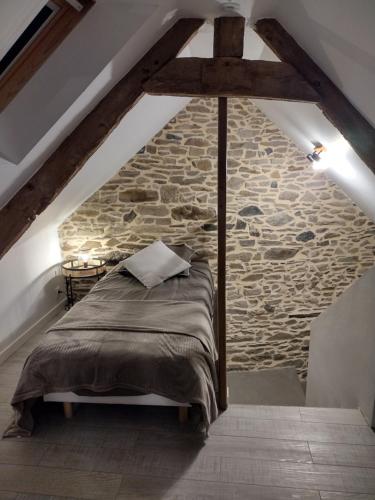 Cama en habitación con pared de piedra en Gîte charmant typique Breton Ti Quartier en Pordic