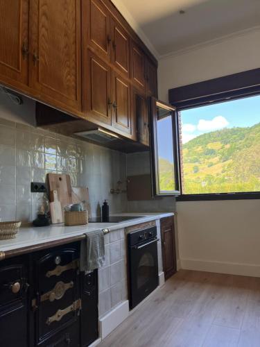 a kitchen with wooden cabinets and a large window at Mountain View Apartment in Mieres
