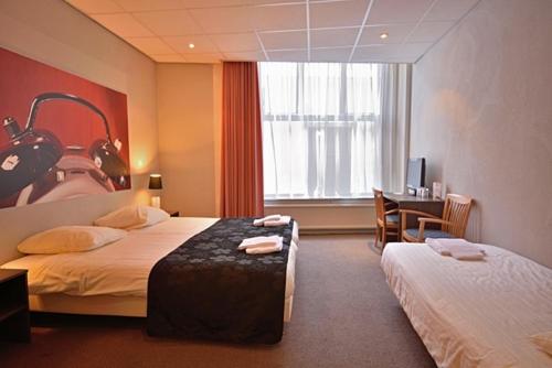 a hotel room with two beds and a desk at Royal in Deventer