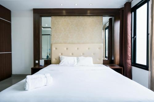 una camera da letto con un grande letto bianco e uno specchio di The Lavana Townhouse Sanur a Sanur