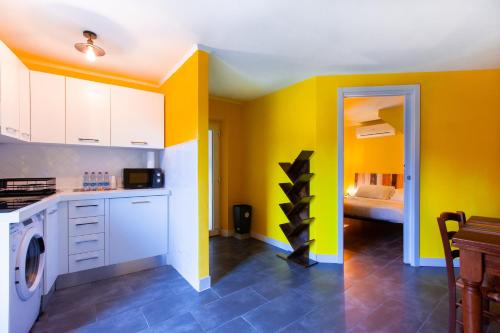 a kitchen with yellow walls and a washer and dryer at Da Aurora al 27 in Manciano
