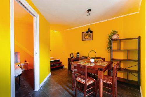 comedor con paredes amarillas, mesa y sillas en Da Aurora al 27, en Manciano