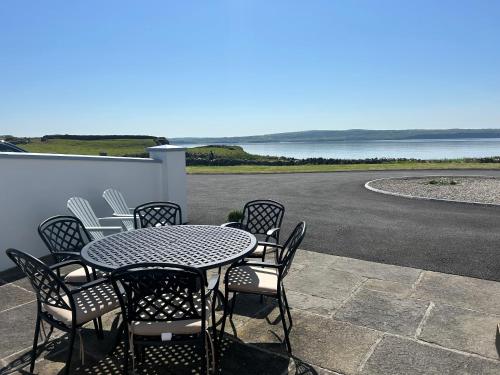 a table and chairs on a patio with a view of the water at Beside the sea & minutes from Cliffs-Clahane Shore Lodge in Liscannor