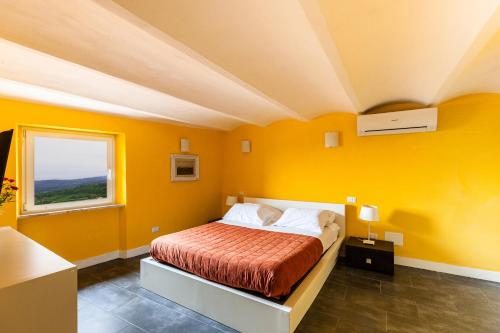 Dormitorio amarillo con cama y ventana en Da Aurora al 27, en Manciano