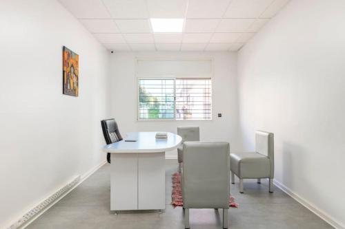 Habitación blanca con escritorio y sillas. en Espace Zen, en Temara