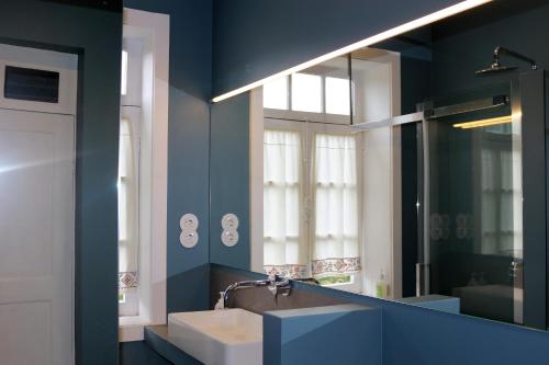 a blue bathroom with a sink and a mirror at Casa de Encosturas in Cabeceiras de Basto