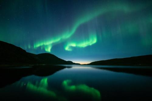 an aurora over a body of water at night at Solsiden Brygge Rorbuer in Ballstad