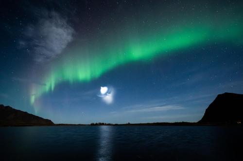 an aurora in the sky over a body of water at Solsiden Brygge Rorbuer in Ballstad