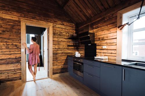 a woman walking into a kitchen with wooden walls at Solsiden Brygge Rorbuer in Ballstad