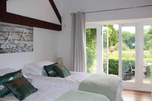 a white bedroom with two beds and a window at Peaceful and tranquil 2 bedroom Deer Cottage in Chippenham