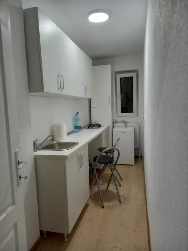 a kitchen with white cabinets and a sink and a chair at Pascani Noul Centru in Paşcani