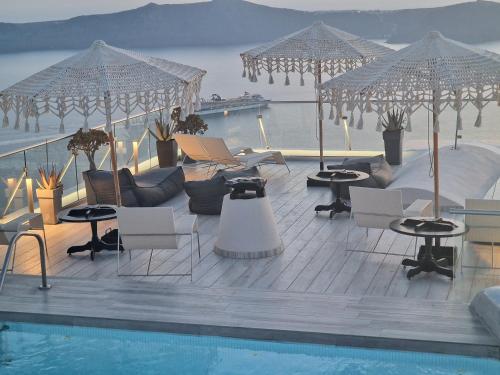a swimming pool with chairs and tables and umbrellas at Galaxy Suites & Villas in Imerovigli