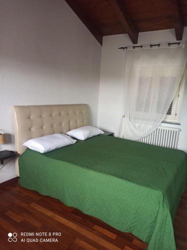 a bedroom with a green bed with a window at sentieri 2 in Pecetto di Valenza
