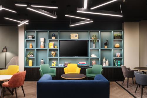 a waiting room with a tv and chairs and tables at Holiday Inn Leeds-Wakefield M1 Jct40 by IHG in Wakefield