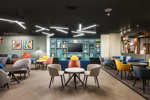 a waiting room with tables and chairs and a flat screen tv at Holiday Inn Leeds-Wakefield M1 Jct40, an IHG Hotel in Wakefield