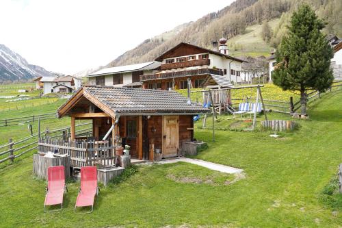 a log cabin with red chairs in front of it at Sesvennahof in Malles Venosta