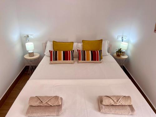 1 cama blanca con 2 almohadas y 2 lámparas en GATU PREMIUM Villa Flamenca, en Cádiz