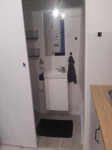 a white bathroom with a sink and a mirror at Apartament nad rzeką in Głuszyca