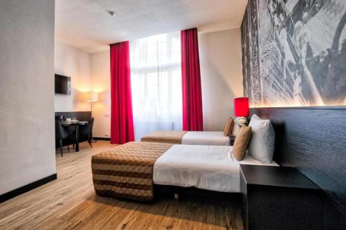 Cette chambre d'hôtel comprend 2 lits avec des rideaux rouges. dans l'établissement Onderwijshotel De Rooi Pannen Tilburg, à Tilbourg