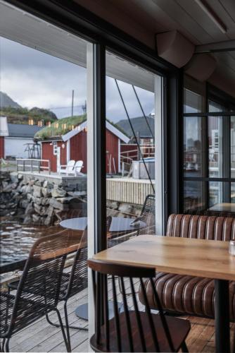 a patio with a table and chairs and a window at Solsiden Brygge Rorbuer in Ballstad
