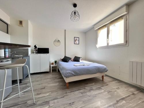 a white bedroom with a bed and a kitchen at Gabriel - B - Studio plein centre ville in Clermont-Ferrand