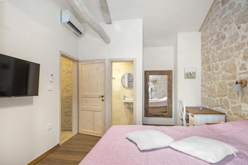 a bedroom with a purple bed with a tv on the wall at Stone house Dijana Istria Sveti Lovrec in Sveti Lovreč Pazenatički