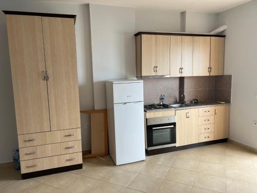 cocina con nevera blanca y armarios de madera en Vlora City Apartments, en Vlorë