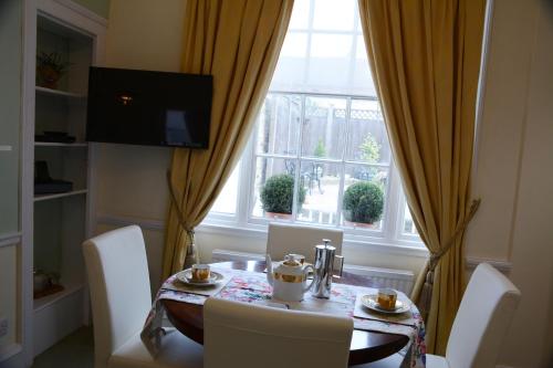 a dining room table with white chairs and a window at Pier View Self Catering Luxury Apartments in Southend-on-Sea