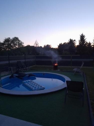 a swimming pool with a grill and chairs around it at Wypoczynek nad Dunajcem in Jurków