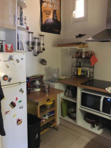 une cuisine avec un réfrigérateur blanc et une table dans l'établissement L'aubaine, à Saint-Aubin-sur-Mer