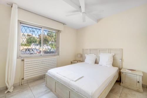 - une chambre avec un grand lit blanc et une fenêtre dans l'établissement Eden Azur, au Golfe-Juan