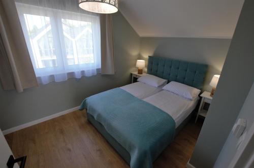 sypialnia z niebieskim łóżkiem i oknem w obiekcie Domki Luan Village we Władysławowie