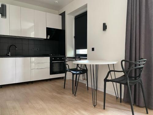 a kitchen with white cabinets and a table and chairs at Електрика 24 на 7 кондиціонер Bordo city center apartment двокімнатні апартаменти в центрі міста in Poltava