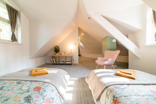 a attic bedroom with two beds and a chair at i’dille Brīvdienu māja in Kuldīga