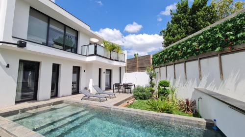 une maison avec une piscine devant une maison dans l'établissement Villa NC30 , chambres privatives deluxe, à La Rochelle